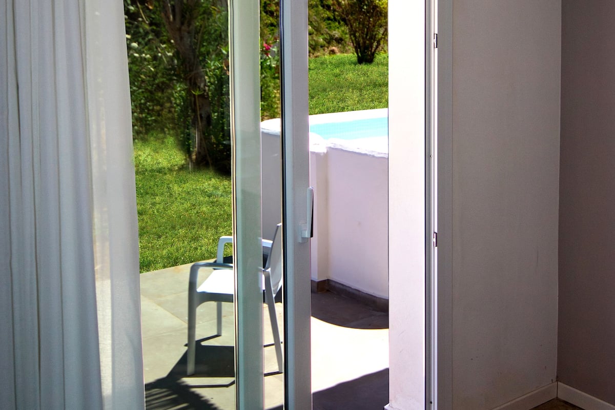 Una stanza con una porta vetrata scorrevole che dà su un patio esterno con piscina e tavolo.
