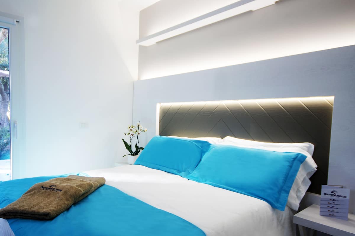 Una camera d'albergo con un letto, un comodino e una finestra.
