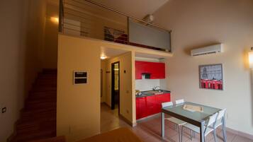 Un appartement moderne comprenant un coin repas, une cuisine et un escalier menant à une mezzanine.