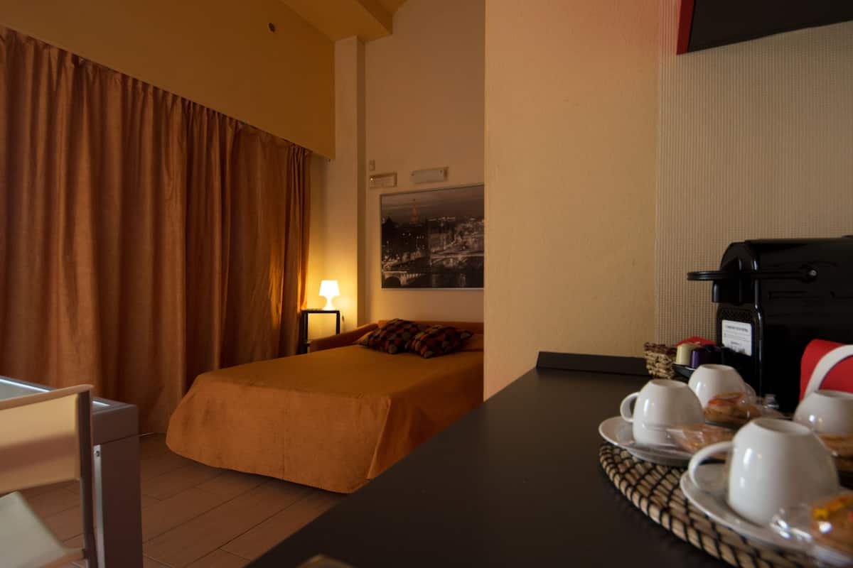 A hotel room with a bed, a desk with a coffee maker, and a breakfast tray.