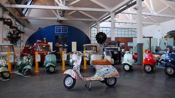 A museum with vintage scooters on display, including a colorful one in the center.