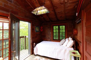 A wooden cabin bedroom with a bed, a small table, and a window. - River's Bend (Saugatuck)