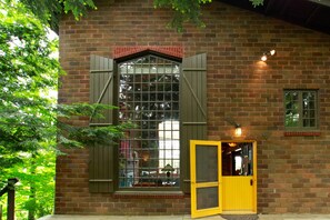 A brick building with a large window and a yellow door. - River's Bend (Saugatuck)