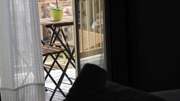 Een balkon met een bloempot en een houten tafel.