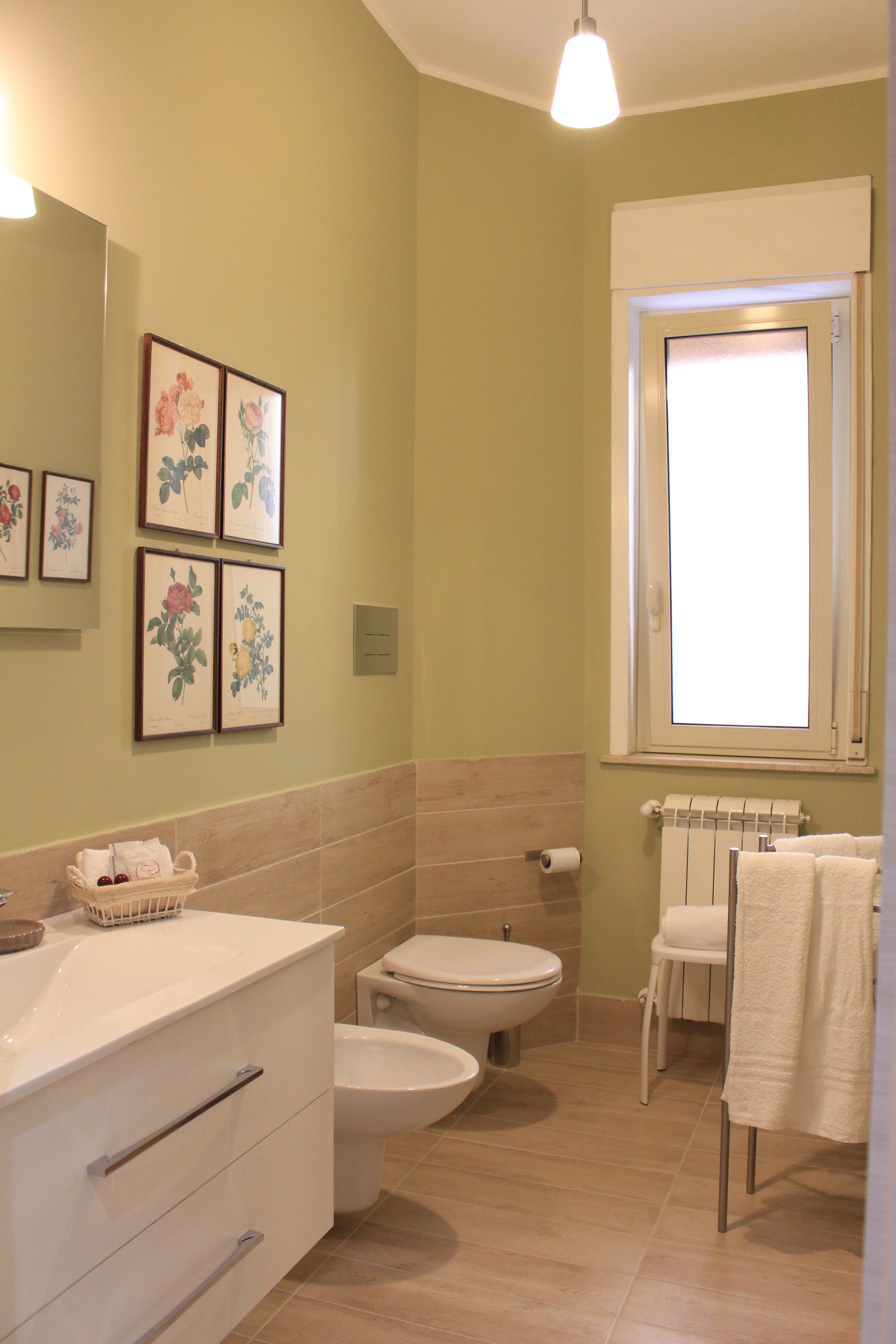 A bathroom with a toilet, bidet, and sink, framed by light green walls and beige tiles.