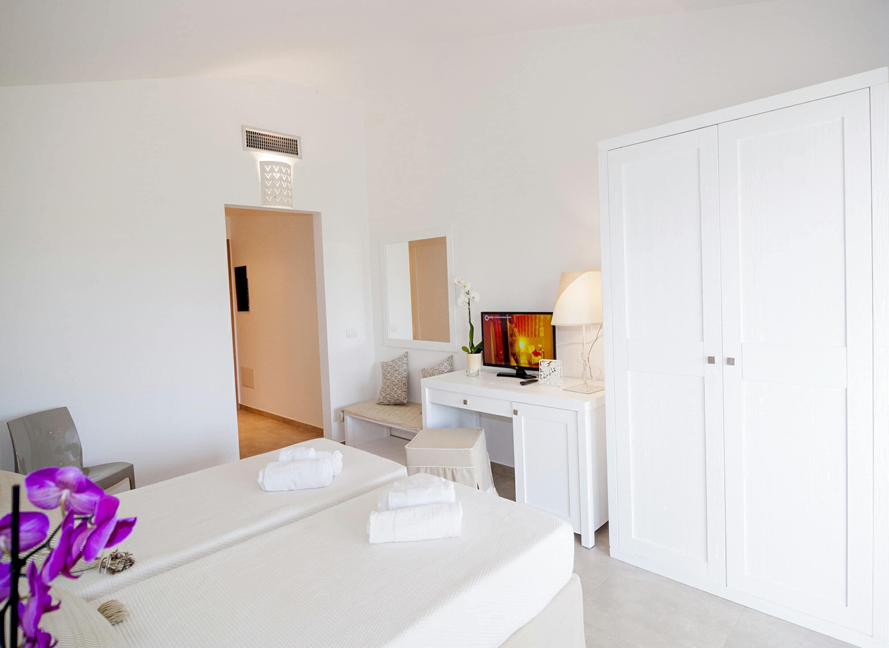 Una habitación de hotel con cama, escritorio, silla, armario y televisor.