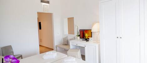 Una habitación de hotel con cama, escritorio, silla, armario y televisor.