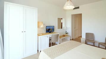 Une chambre d’hôtel équipée d’un lit, d’un bureau avec un ordinateur, d’une chaise, d’une télévision et d’une armoire.
