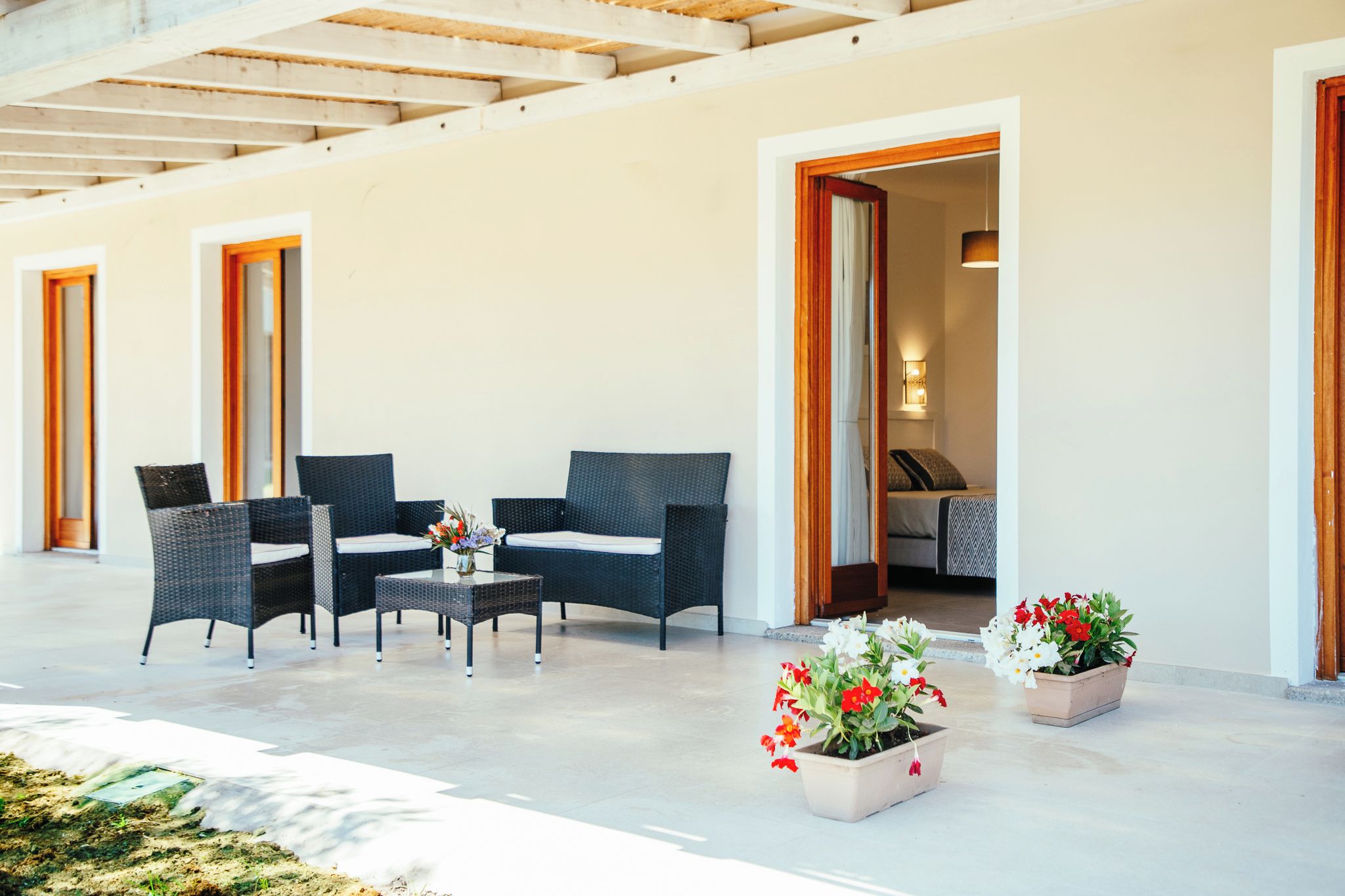 A covered outdoor seating area with wicker furniture and potted plants.
