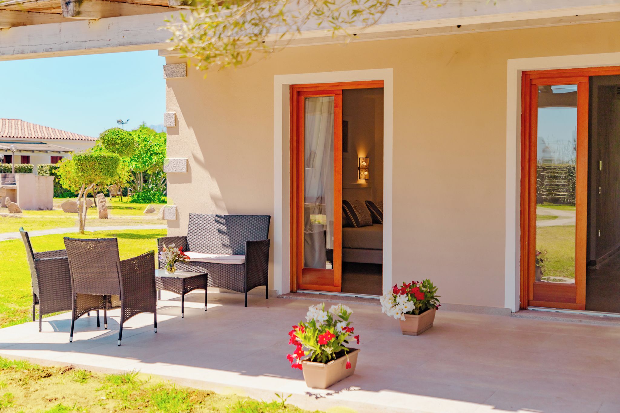 A covered outdoor seating area with wicker furniture and potted plants.