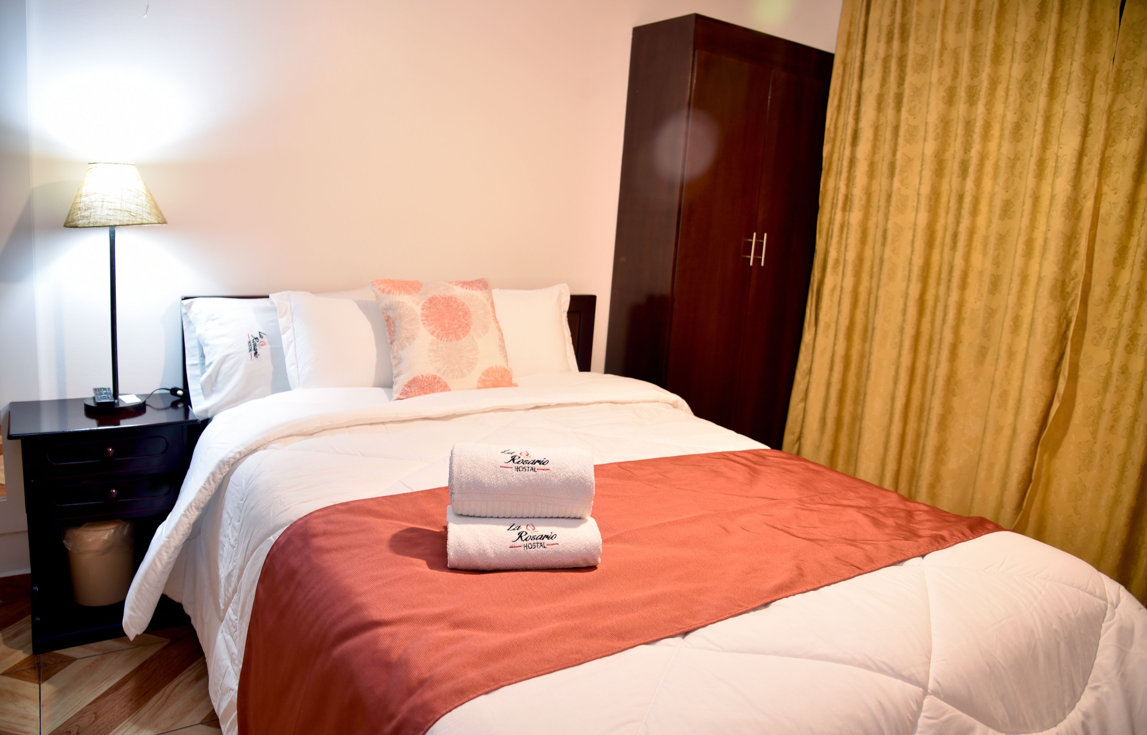 Ein Hotelzimmer mit Bett, Nachttisch, Lampe und Kleiderschrank.