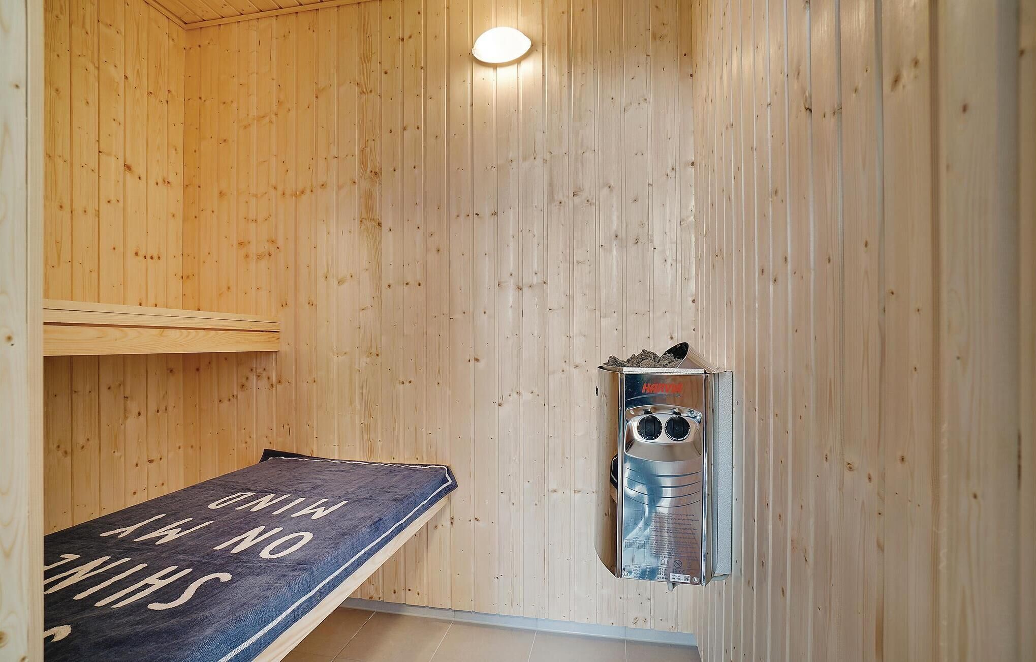 Un sauna avec des murs en bois, un banc portant une inscription et un appareil de chauffage pour sauna.