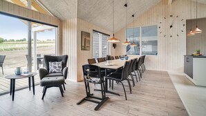 A spacious dining area with a long table and chairs, large windows, and a view of the outdoors. - Stunning home in Vejby with sauna (Vejby)
