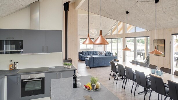 A modern kitchen with grey cabinets, a built-in oven, and a dining area with a large table and chairs. - Stunning home in Vejby with sauna (Vejby)