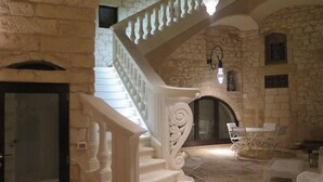 A stone-walled interior with a white staircase, a fireplace, and outdoor seating. - Dimora dell'Osanna (Carovigno)
