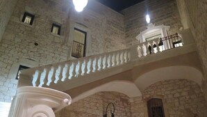 A stone building with a balcony, a fireplace, and a light fixture. - Dimora dell'Osanna (Carovigno)