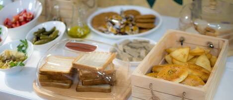 A table with various food items including sandwiches, pickles, and pastries.