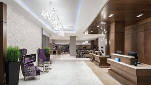 Een moderne lobby met een receptiebalie, zithoek en een open haard.