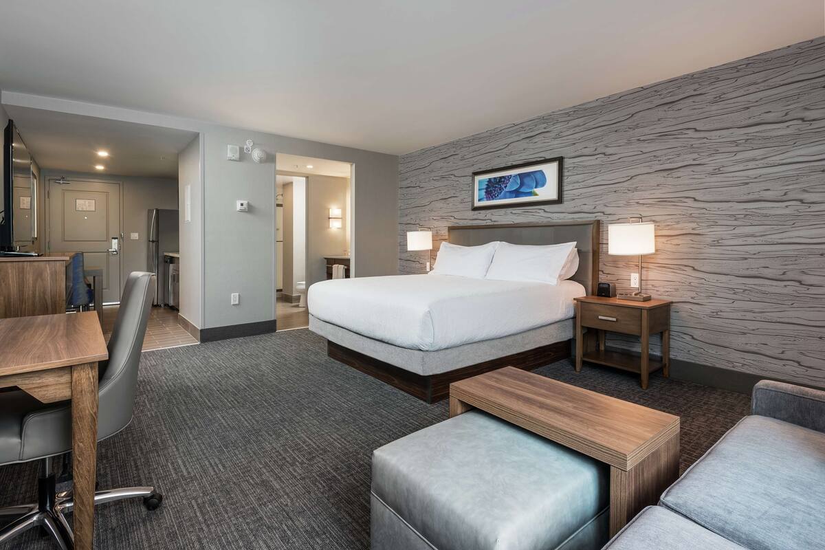 Une chambre d’hôtel avec un lit, un bureau, une chaise, un canapé et une petite table.