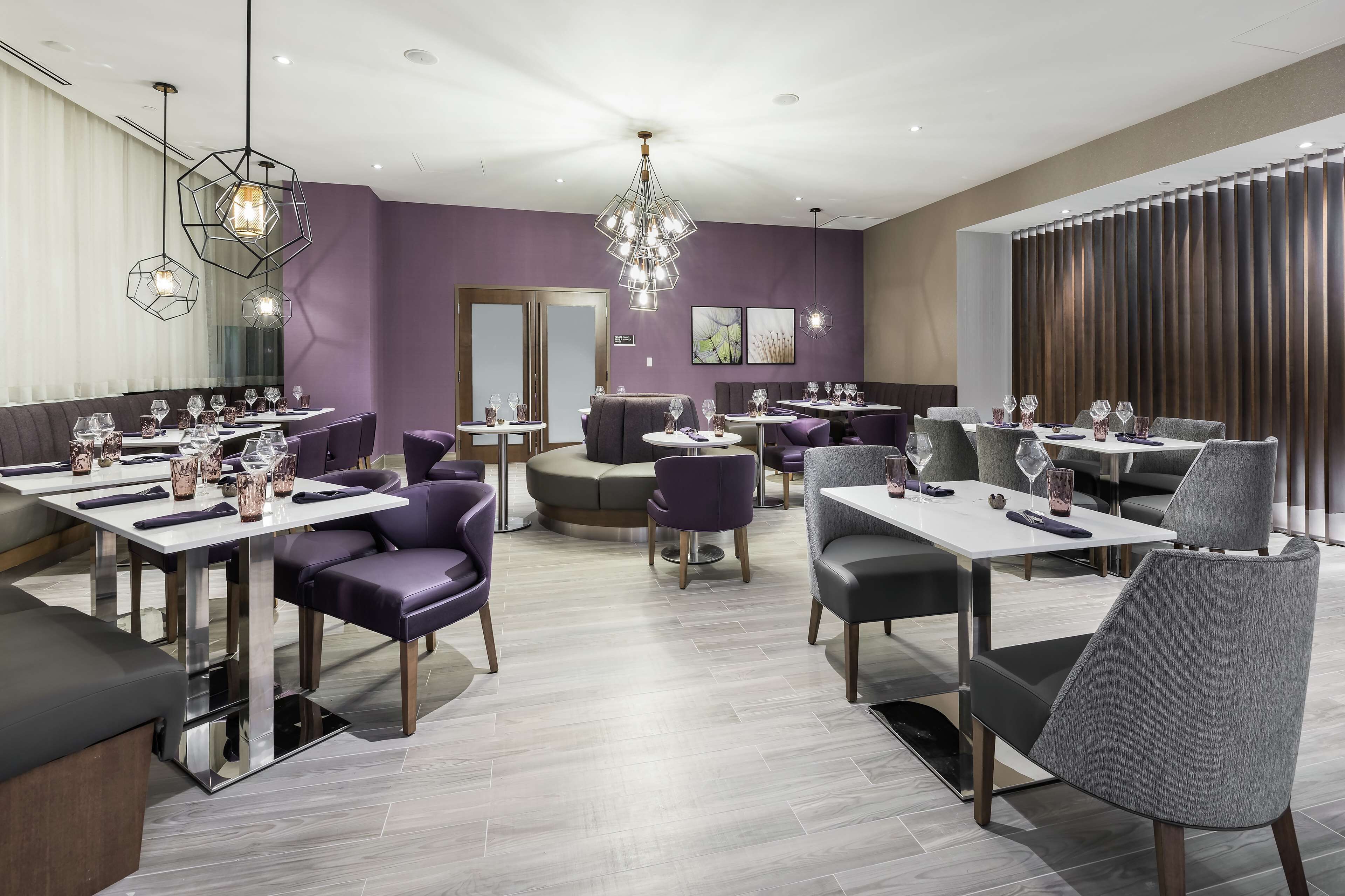 Un restaurante moderno con varias zonas de comedor, incluyendo mesas redondas y cabinas, y diversas opciones de asiento.