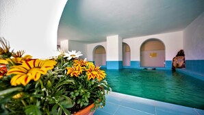 A pool area with a tiled floor and a potted plant with yellow flowers. - Hotel La Mandorla (Barano d'Ischia)