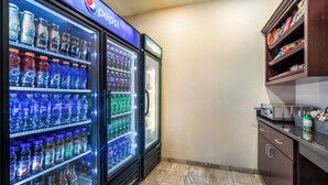 Uma área com máquinas de venda automática de Pepsi e Gatorade, um refrigerador e uma prateleira de lanches.