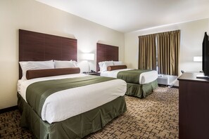 A hotel room with two beds, a desk, a TV, and a window with curtains.