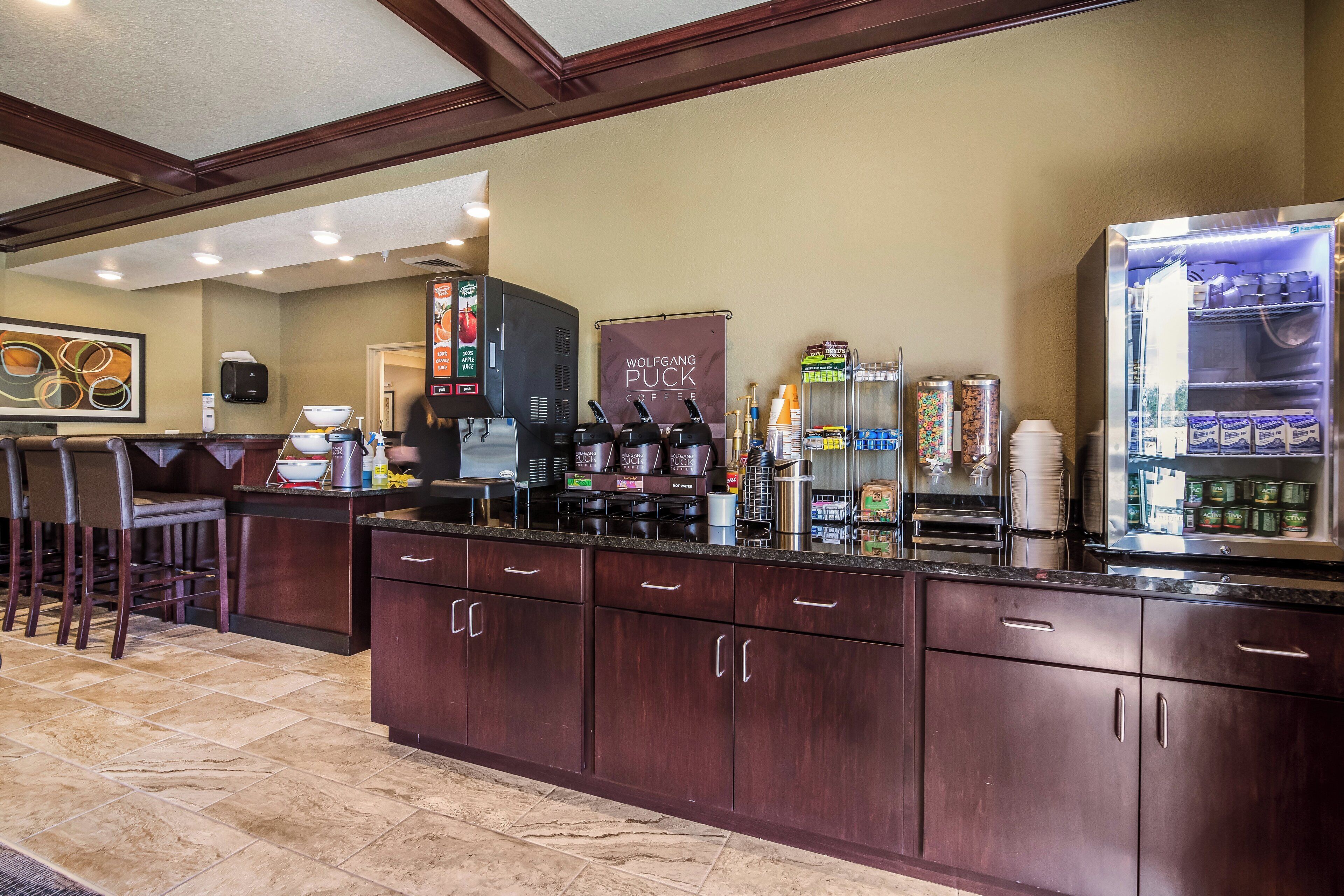 Un hall de hotel con una barra de café, zona de estar y un refrigerador grande lleno de bebidas.