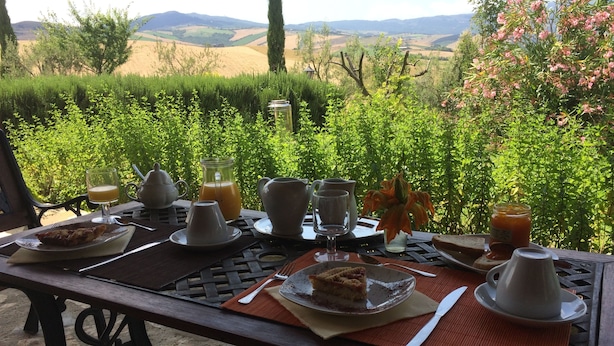 A table set for breakfast with plates, glasses, and a pitcher of orange juice, overlooking a scenic landscape. - Sant'Apollinare (Piancastagnaio)
