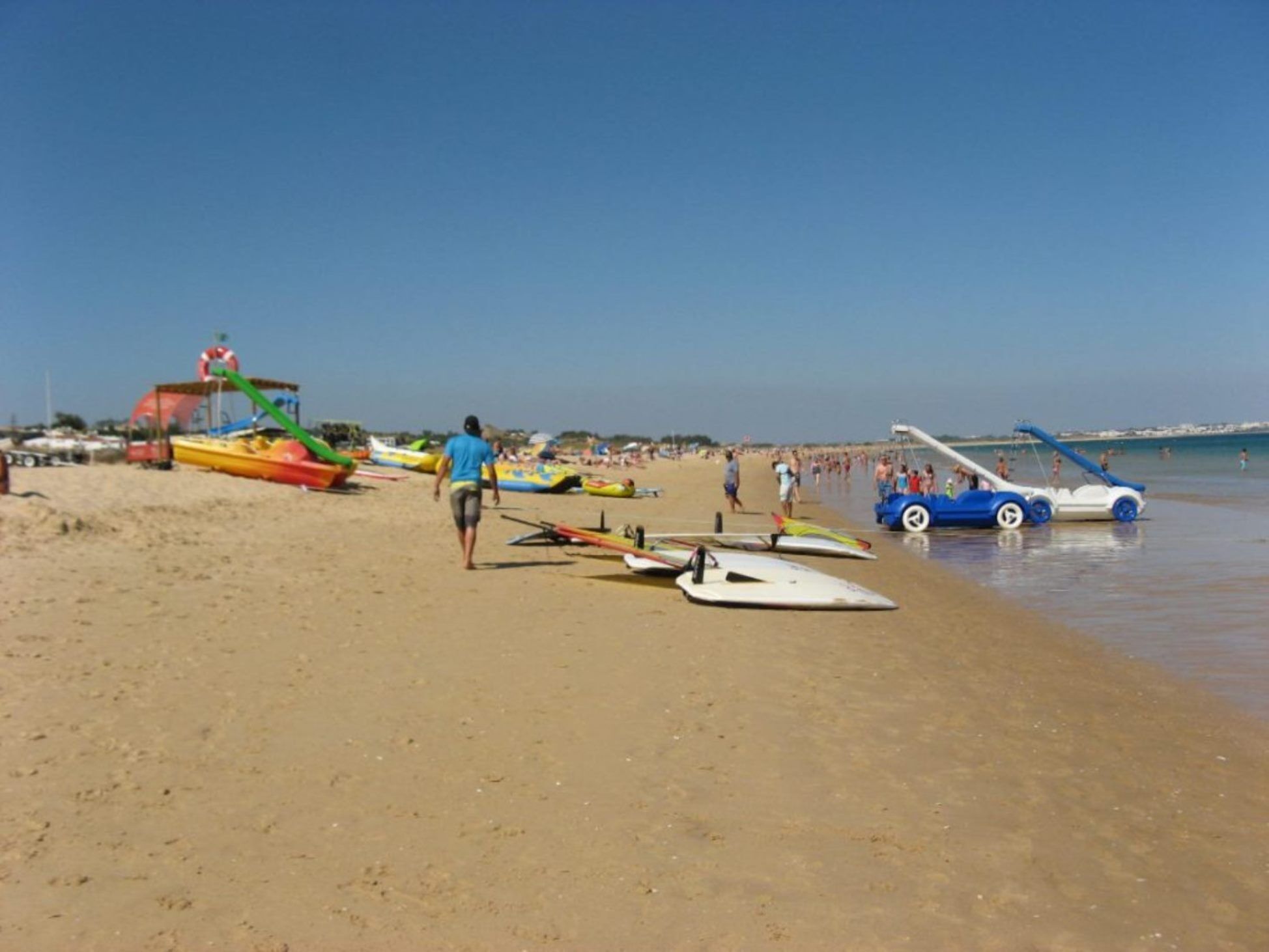 A beach with various watercraft and people.