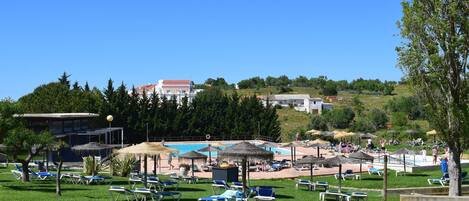 A resort with a pool area, sun loungers, and umbrellas.