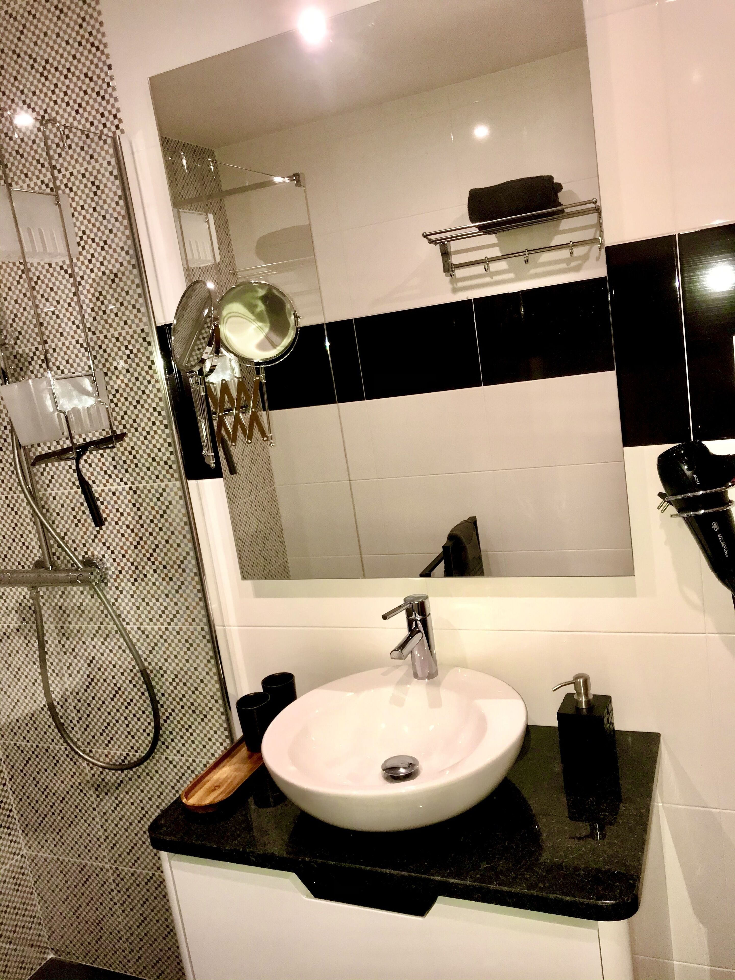 A bathroom with a white sink, black countertop, and a large mirror above the sink.