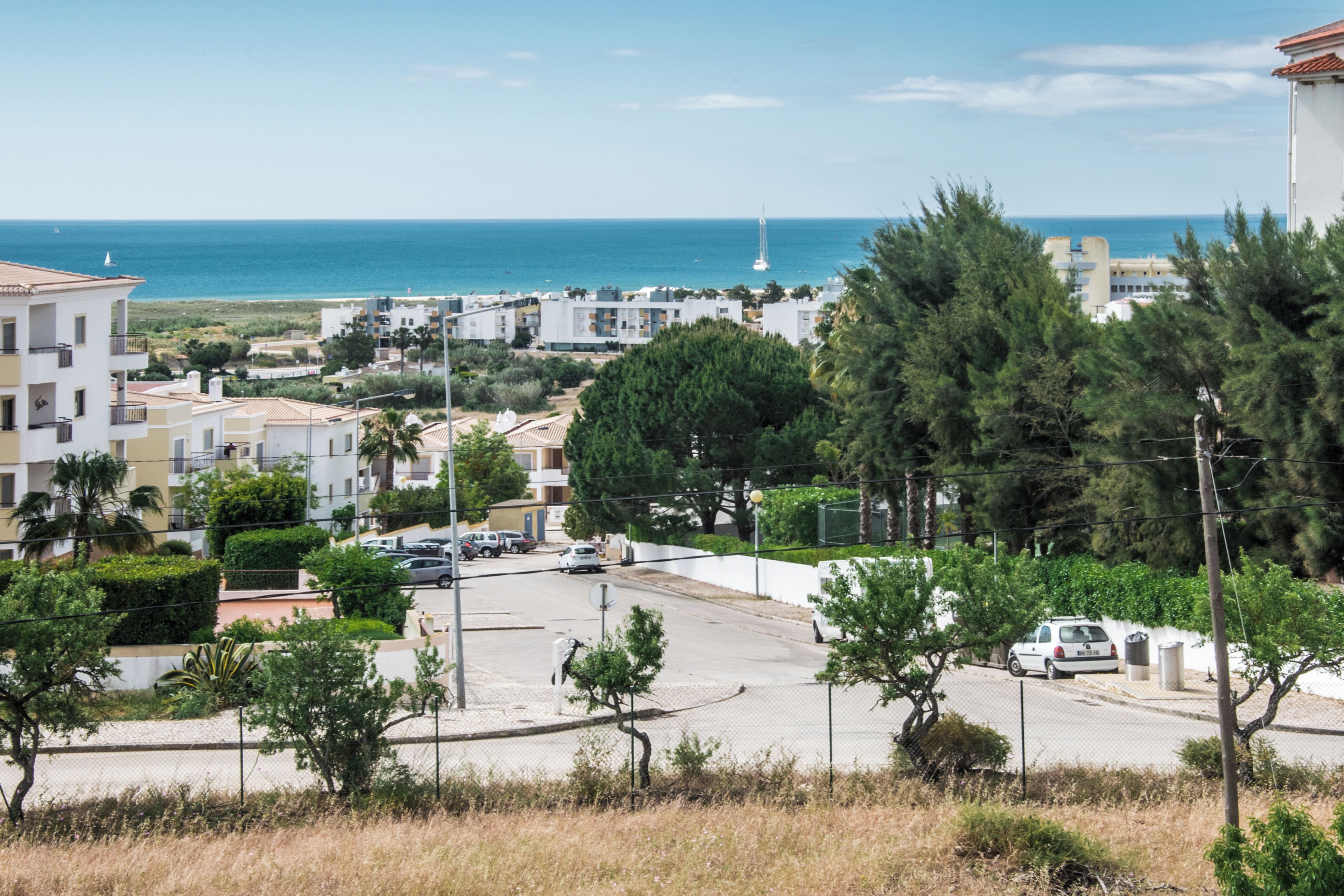 A coastal residential area with buildings, a road, and a view of the sea.
