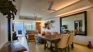 A spacious living area with a dining table, chairs, sofas, and a large mirror. - Wake Up To Sounds Of The Ocean Condo (Puerto Vallarta)