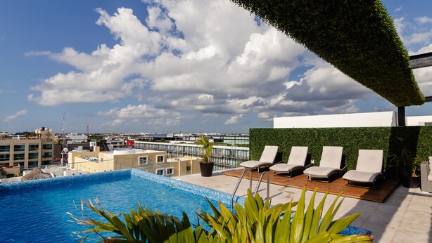 Una piscina en la azotea con sillas de descanso y vistas de la ciudad.