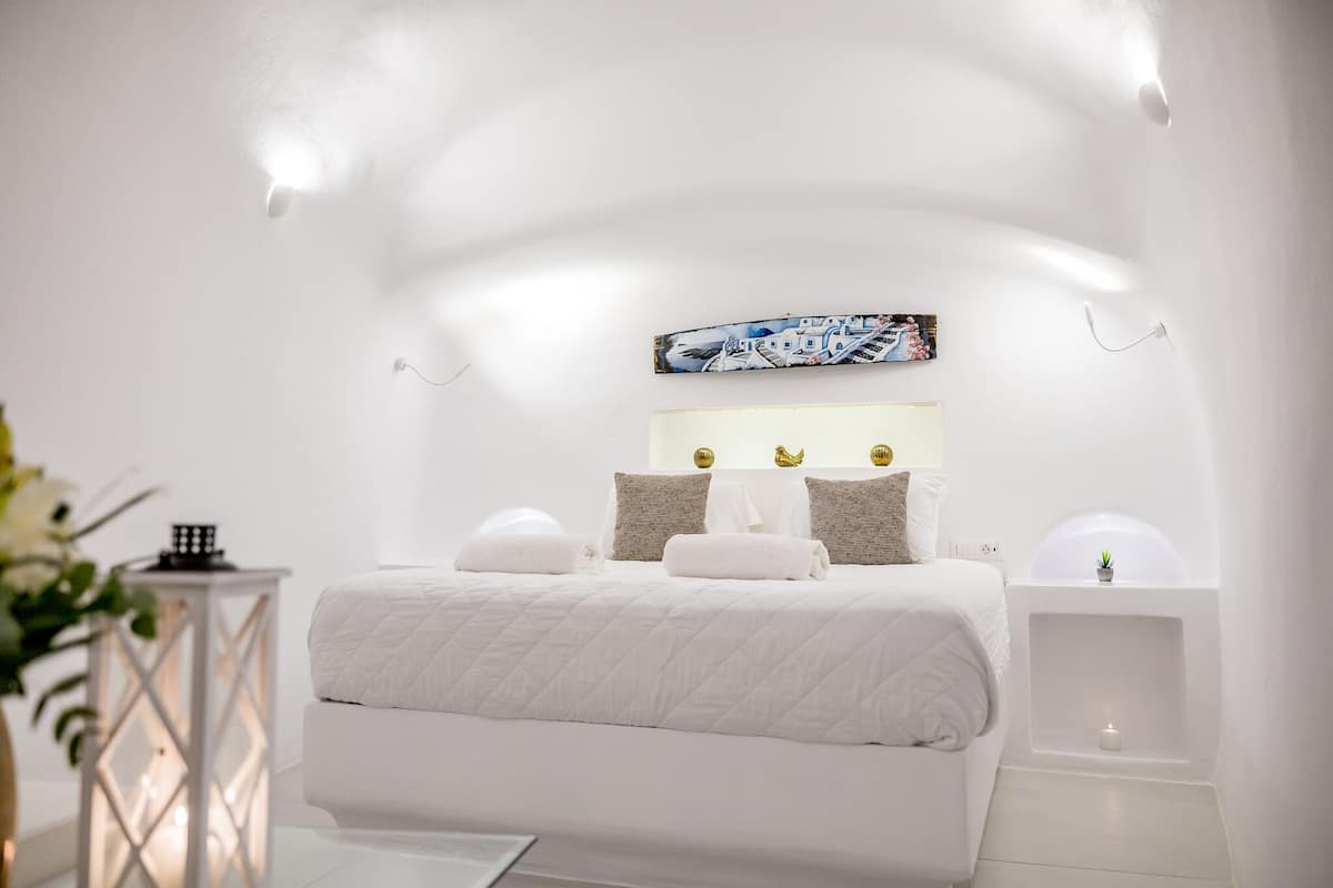 Ein modernes, minimalistisches Schlafzimmer mit einem großen Bett, Nachttischen und einer Wandleuchte.
