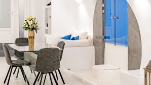 Un interior moderno con zona de comedor, un sofá y vistas a través de un ventanal.