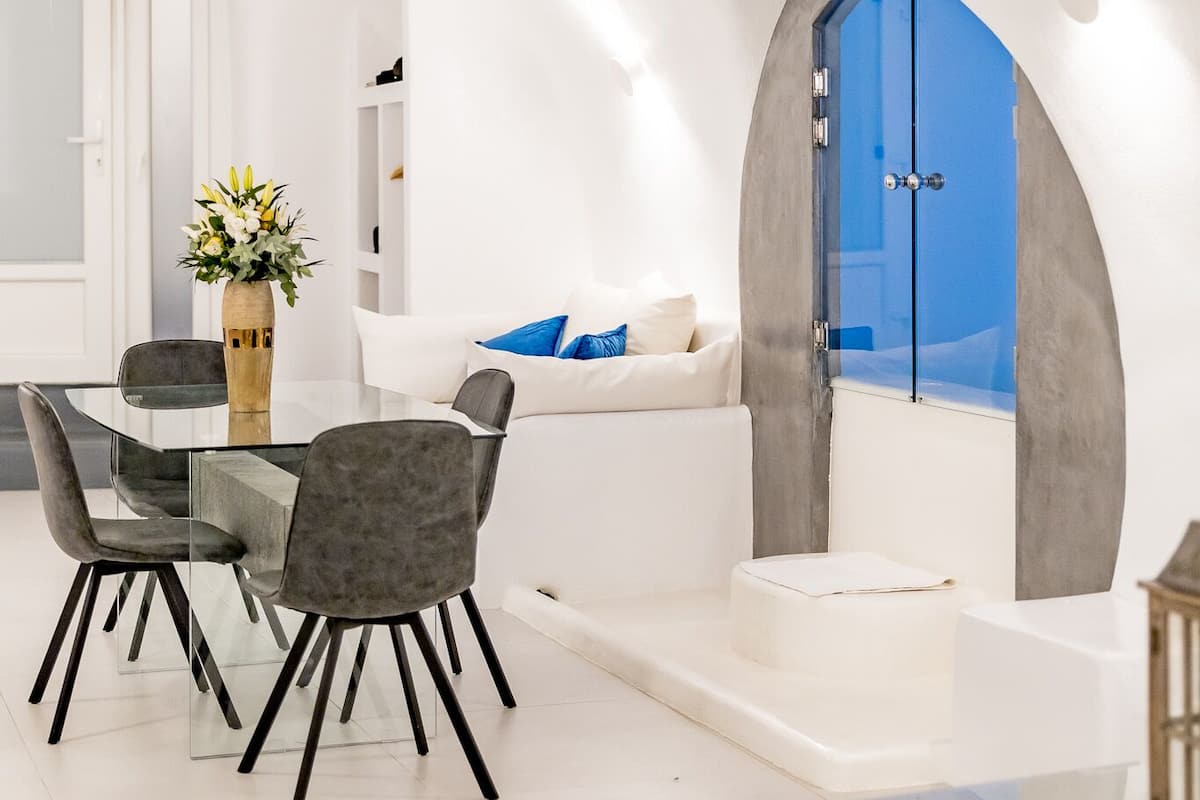 Ein modernes Interieur mit Essbereich, einer Couch und Blick durch eine Glastür.