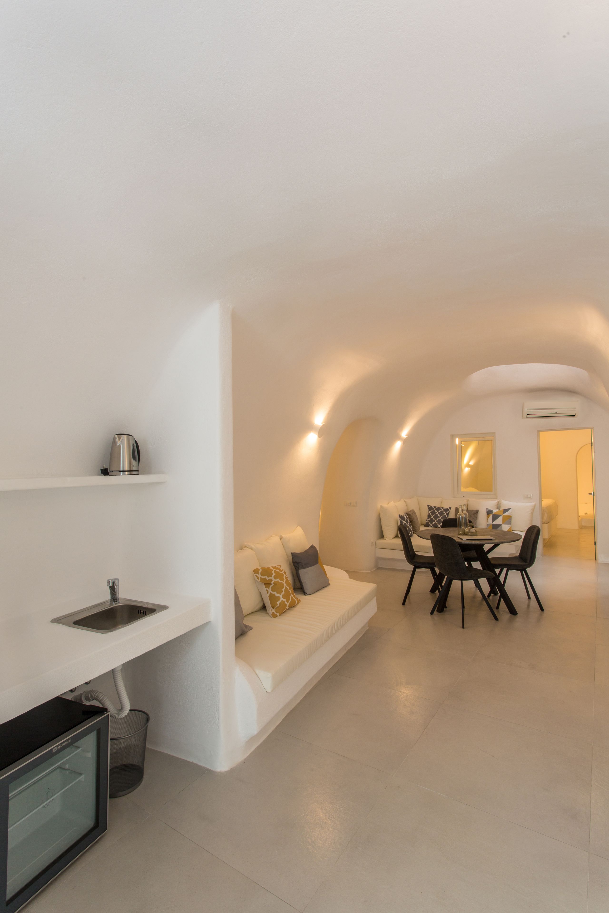 Un espacio habitable moderno y minimalista con sofá, mesa de comedor y zona de cocina.