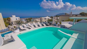 Piscina en la azotea con sillones de descanso y vista al mar y edificios.