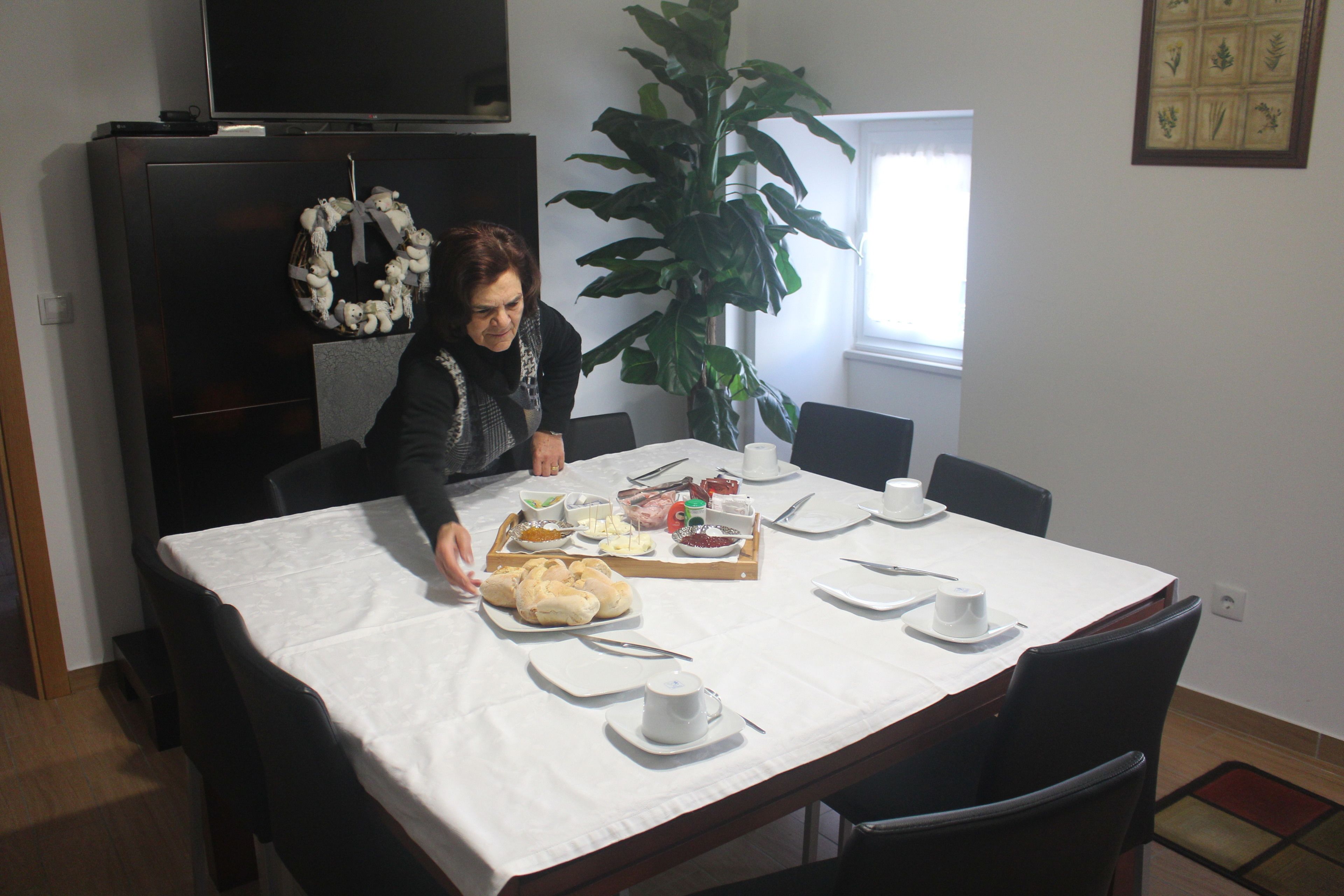 A dining table set with various dishes, a large potted plant, and a television above.