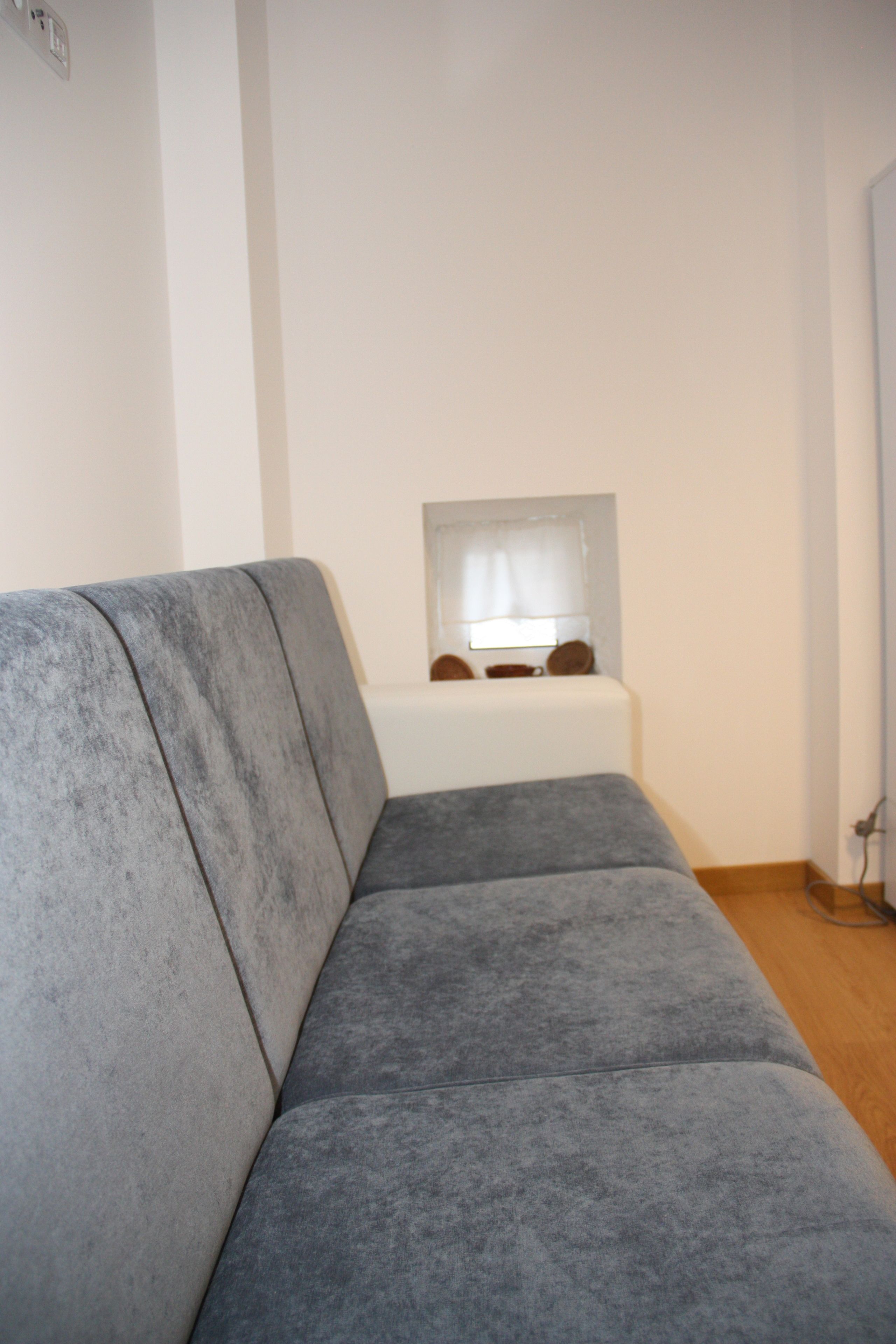 Un sofá gris en una habitación con una ventana y una puerta.