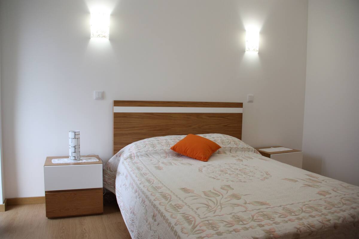 A bedroom with a bed, nightstands, and a wooden headboard.