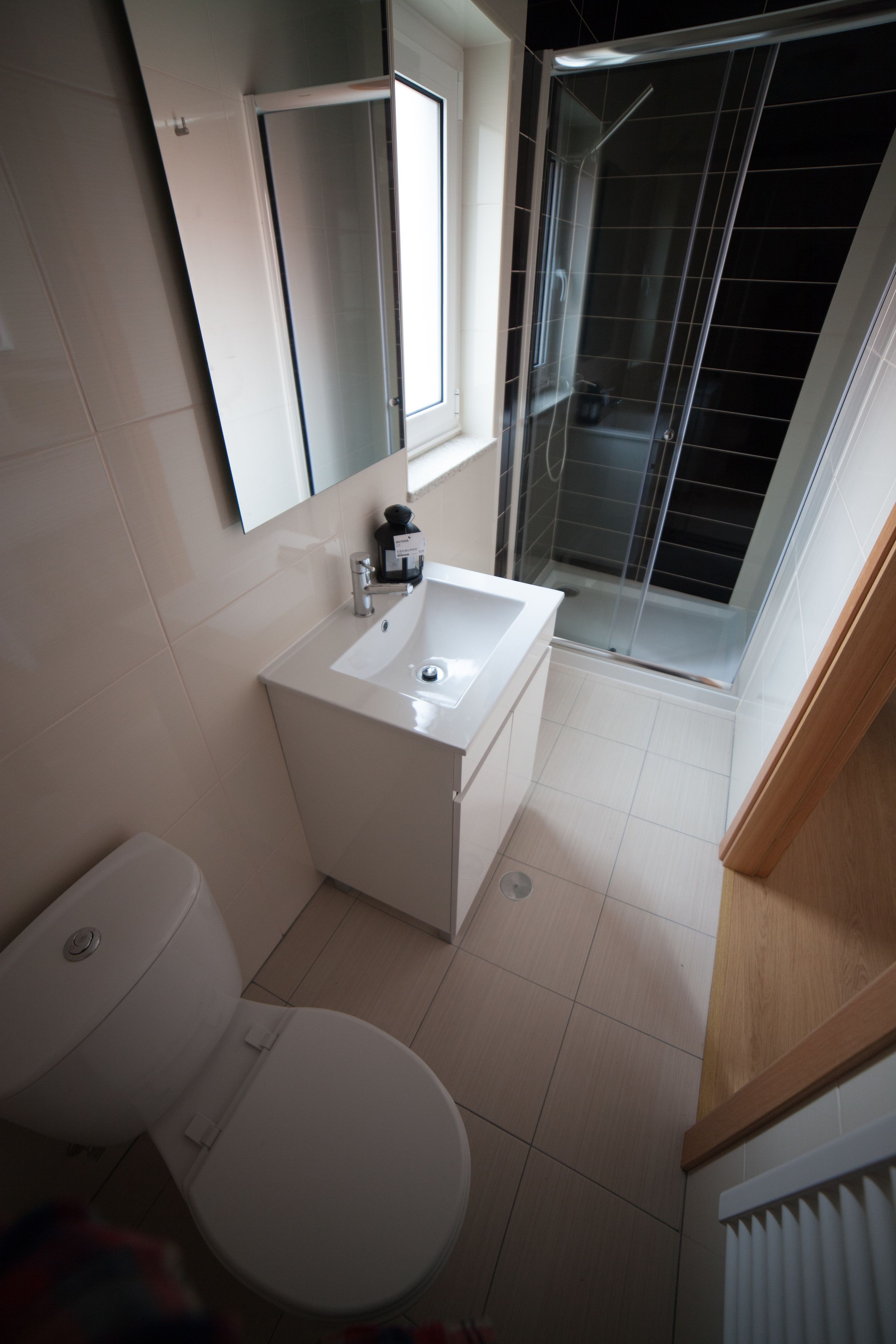 A modern bathroom with a toilet, sink, and glass shower enclosure.