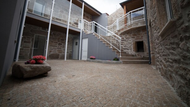 A courtyard with stone flooring, a stone wall, and a staircase leading to an upper level. - Pátio da Caetana (Almeida)