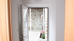 A modern room with a glass sliding door leading to a stone wall and a hanging planter. - Pátio da Caetana (Almeida)