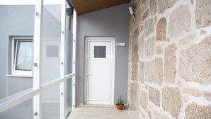 A modern building with a stone facade, a glass door, and a small potted plant. - Pátio da Caetana (Almeida)