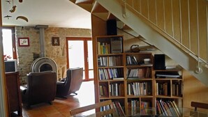 Un vaste espace de vie agrémenté d’une cheminée, d’une grande bibliothèque et d’une table en verre aux lignes courbes.