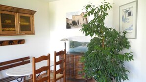 Un coin repas avec des chaises en bois et une table ronde, une plante en pot et des œuvres d’art accrochées au mur.