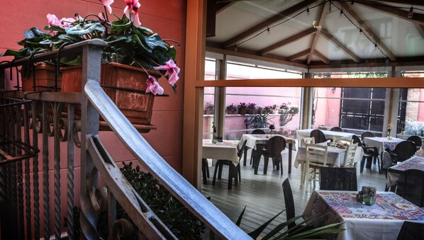 An outdoor patio area with tables and chairs, a staircase with metal railings, and potted plants.